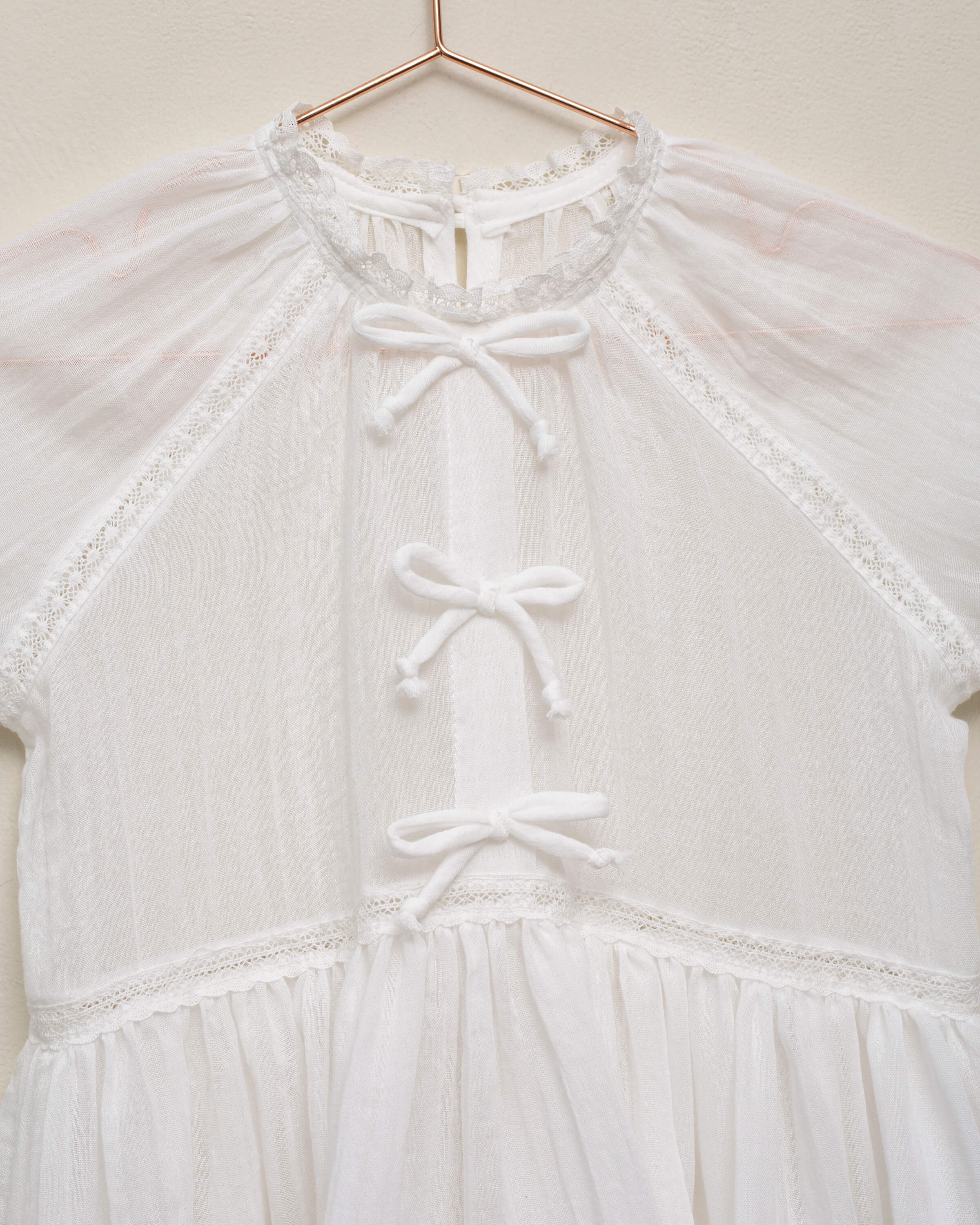 Vestido en blanco roto con lazitos en el pecho y encajes, falda con lorzas y pololos a juego Cosmosophie