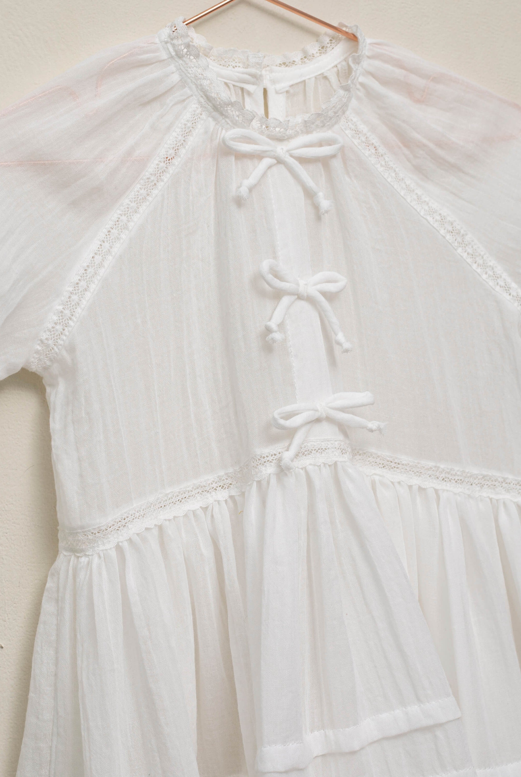 Vestido en blanco roto con lazitos en el pecho y encajes, falda con lorzas y pololos a juego Cosmosophie