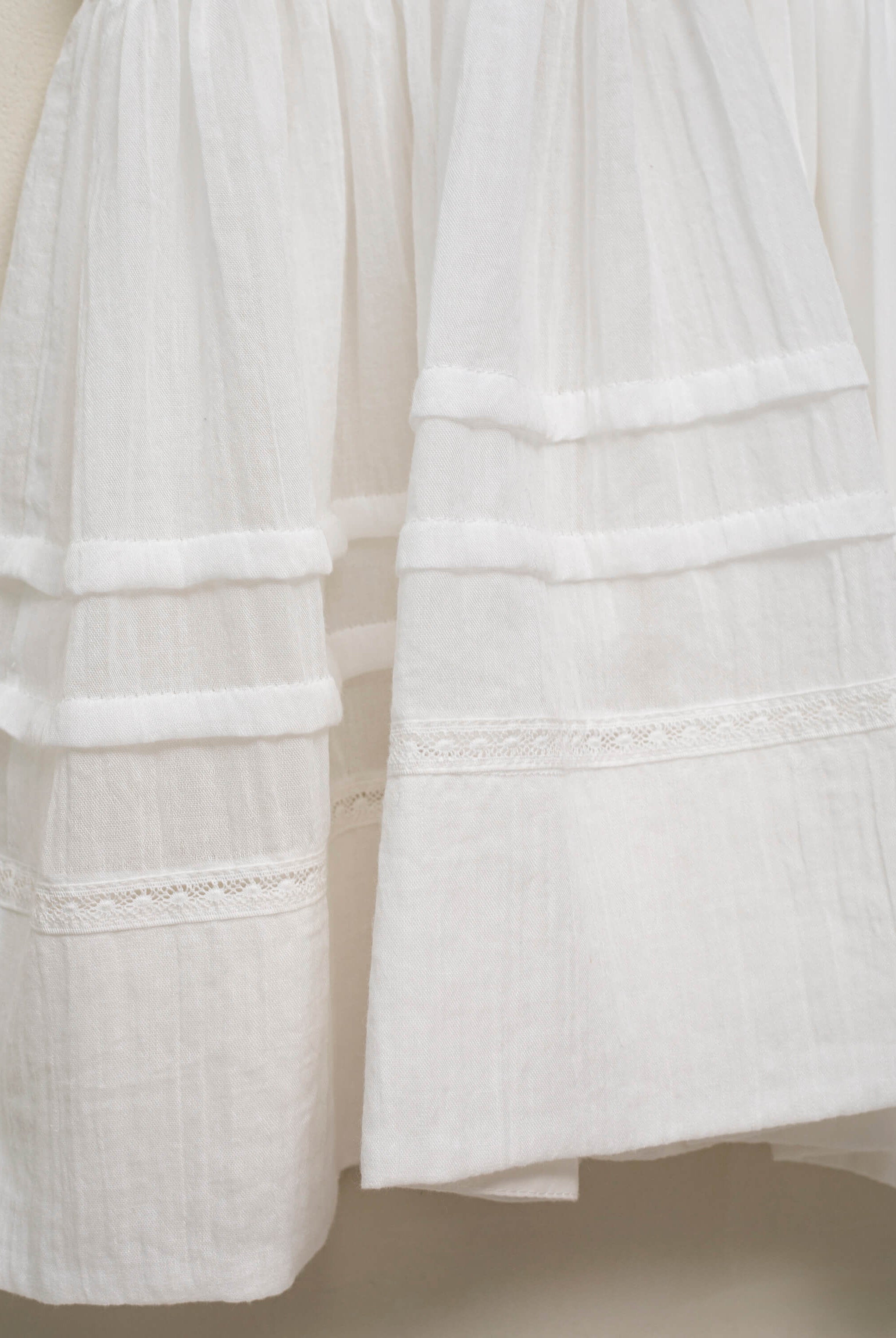 Vestido en blanco roto con lazitos en el pecho y encajes, falda con lorzas y pololos a juego Cosmosophie