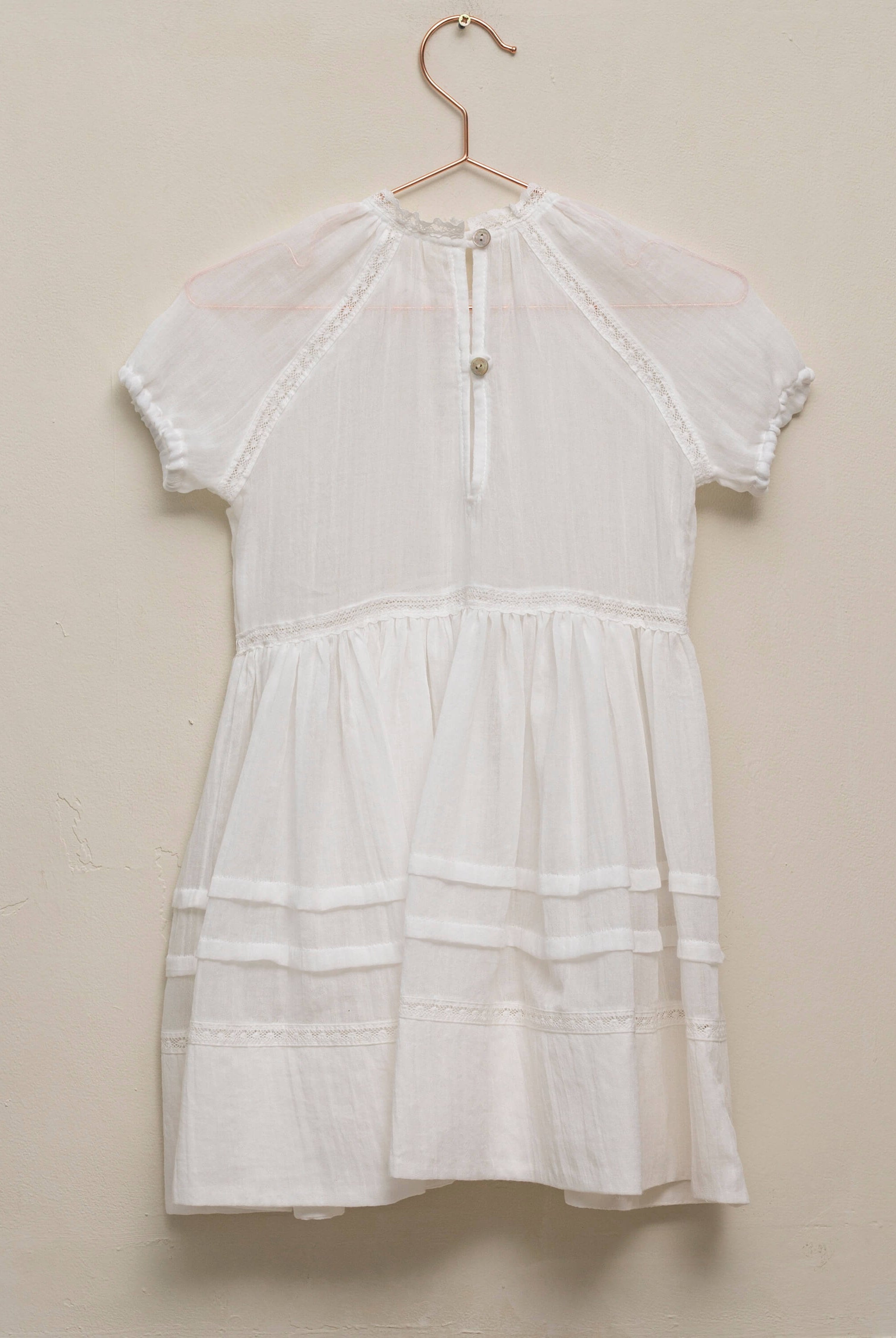 Vestido en blanco roto con lazitos en el pecho y encajes, falda con lorzas y pololos a juego Cosmosophie