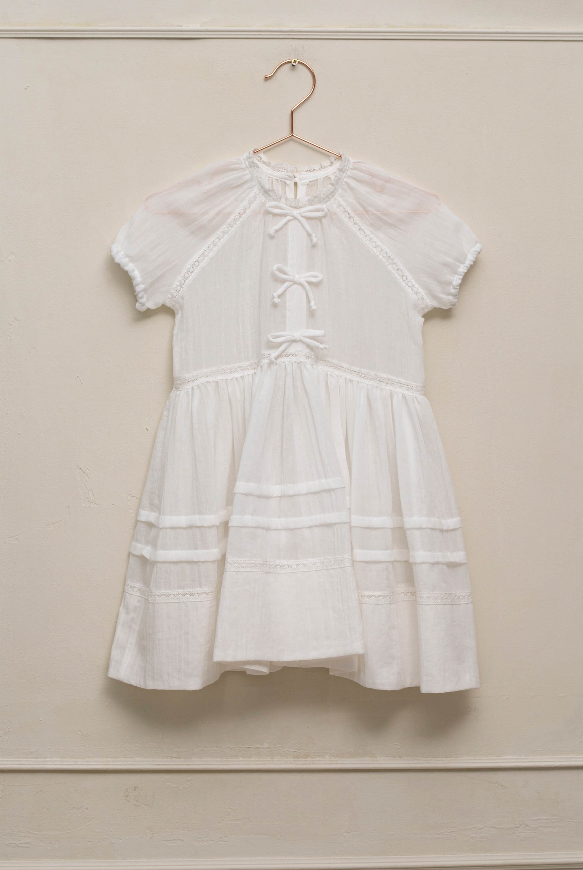 Vestido en blanco roto con lazitos en el pecho y encajes, falda con lorzas y pololos a juego Cosmosophie