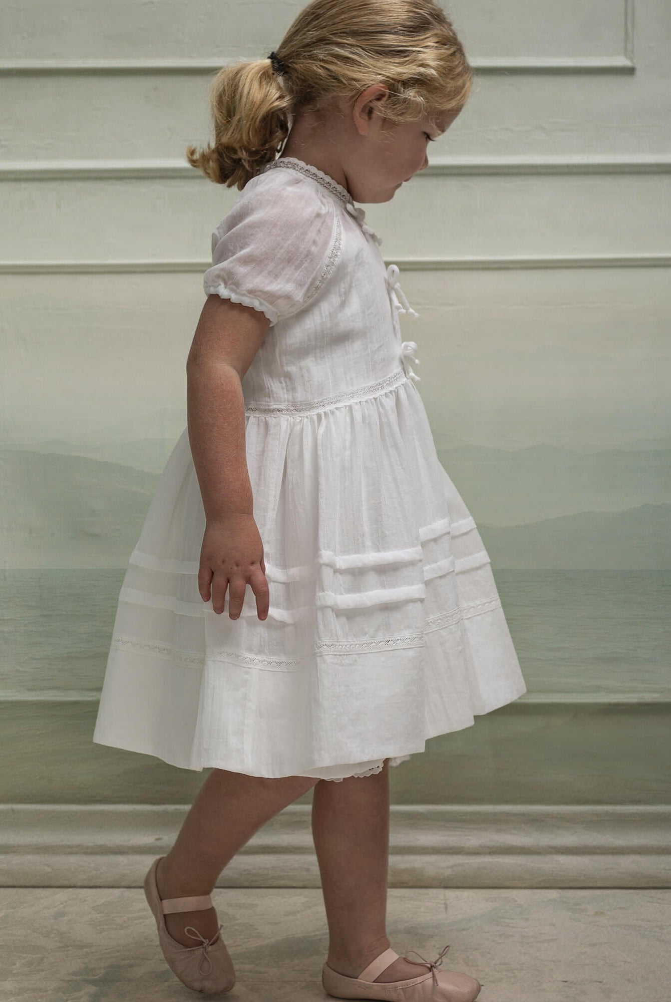 Vestido en blanco roto con lazitos en el pecho y encajes, falda con lorzas y pololos a juego Cosmosophie