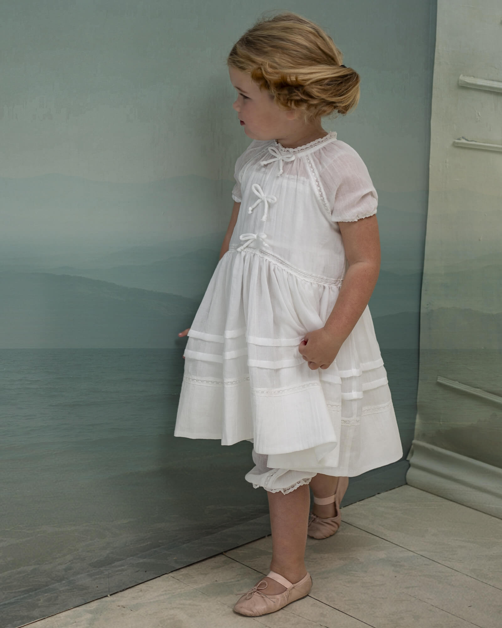 Vestido en blanco roto con lazitos en el pecho y encajes, falda con lorzas y pololos a juego Cosmosophie