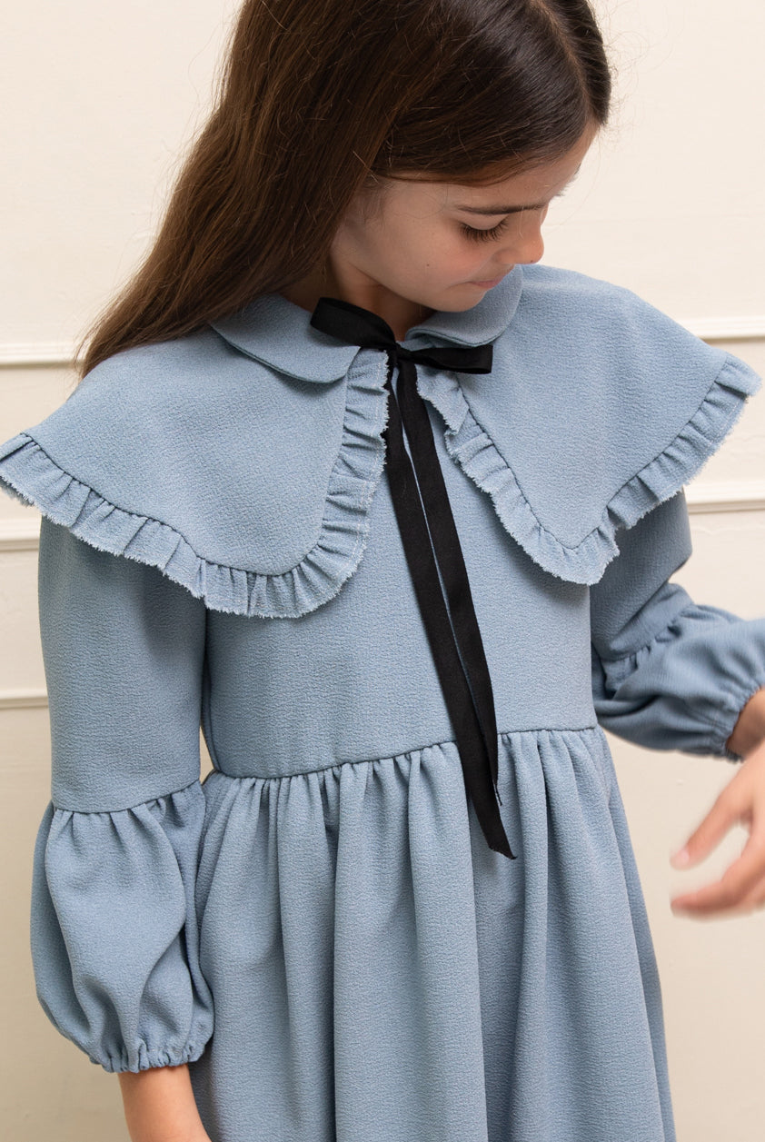 Vestido azul celeste con capita con volantes y lazo negro. cosmosophie