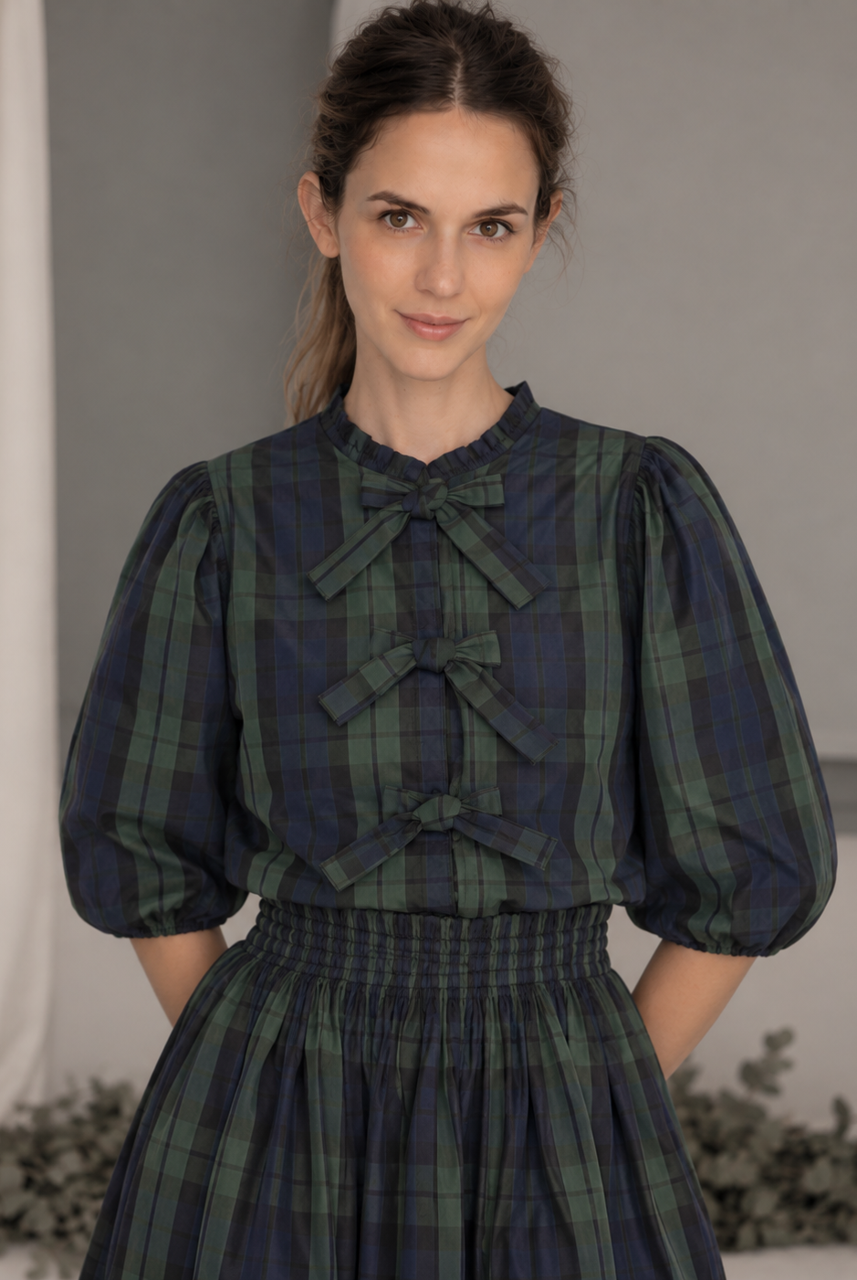 Blusa de tafetán de cuadros en verde y azul marino, con manga al codo y cierre delantero con lazos. Diseño elegante confeccionado en Madrid.