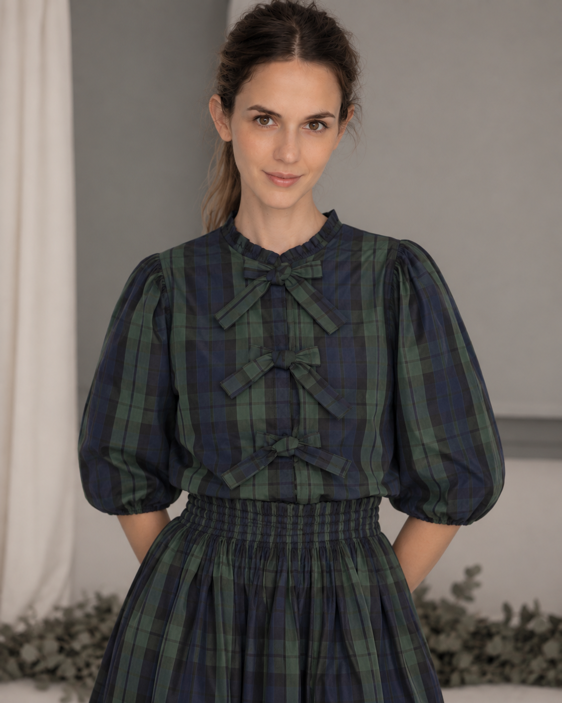 Blusa de tafetán de cuadros en verde y azul marino, con manga al codo y cierre delantero con lazos. Diseño elegante confeccionado en Madrid.