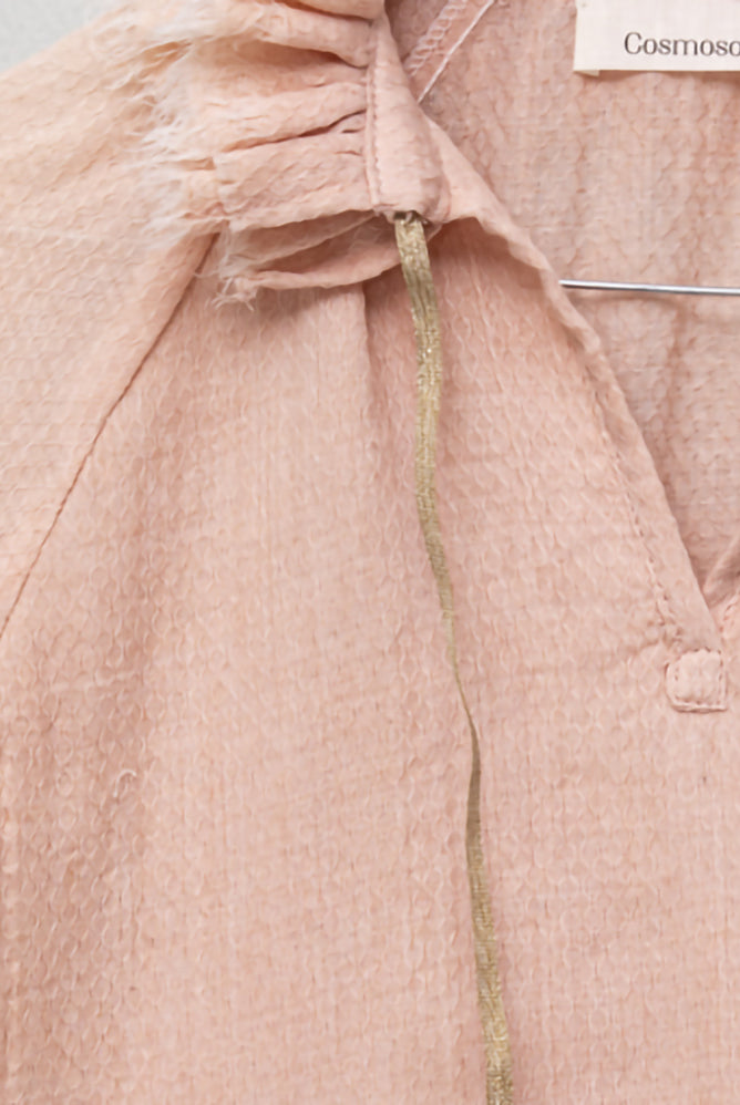 Blusa de mujer rosa con efecto jacquard, cuello de volantes deshilachados y cordones dorados. Diseño femenino y especial.