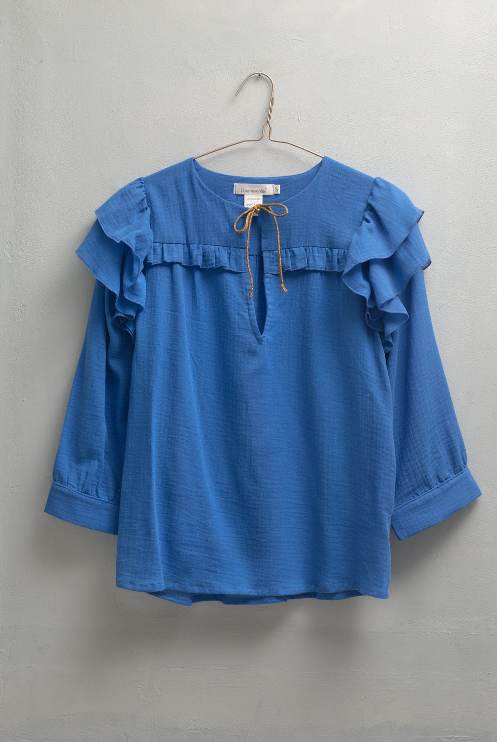 Blusa en algodon vaporoso azul cian con doble volante en el hombro y lazada en oro
