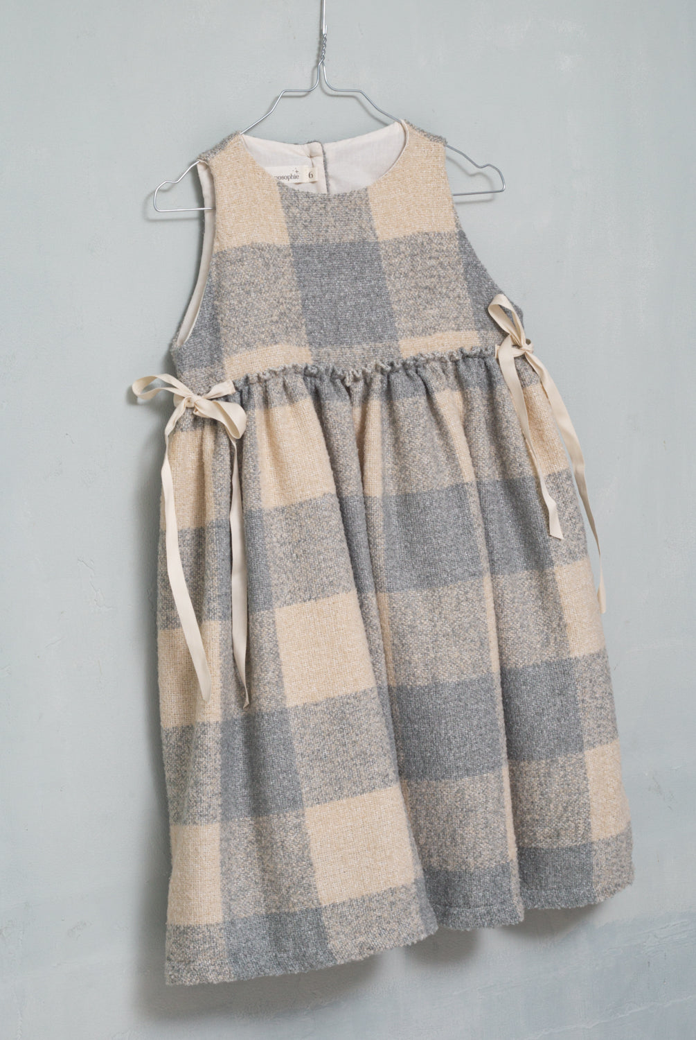 Beautiful pinafore dress in soft oversize gingham fabric in ecru and bluish grey. Perfect to wear with one of our ruffle neck blouses. You will love its bows on the sides.