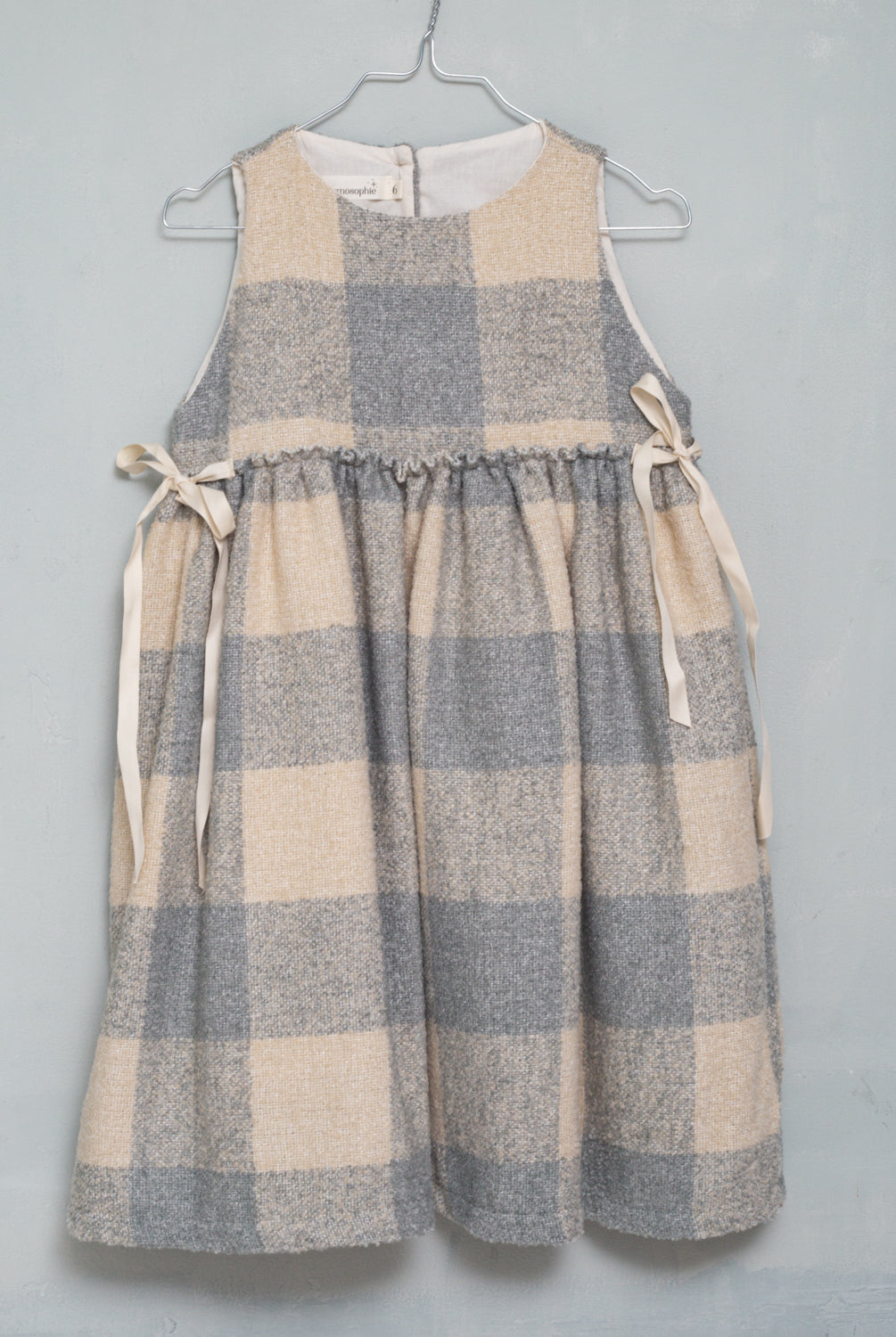 Precioso pichi en suave tejido de vichy oversize en color crudo y gris azulado. Perfecto para llevar con una de nuestras blusas de cuello de volantes. Te encantarán sus lazadas en los lados.