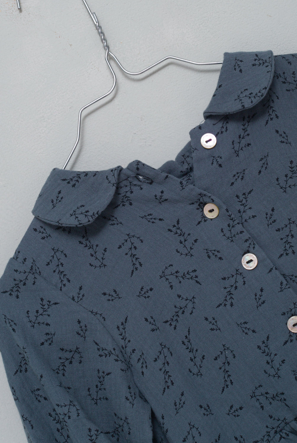 Front button dress with baby collar. You will love its blue double gauze fabric with a print of small black flowers. As details, it has a black ribbon that is tied at the waist.