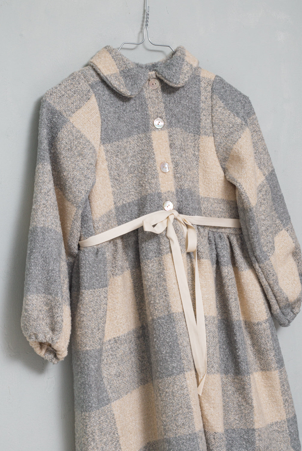 Vestido abierto por delante con botones y cuello bebe. Te encantrá su tejido de vichy oversize. Como detalle, lleva una cinta en crudo que se anuda en la cintura.