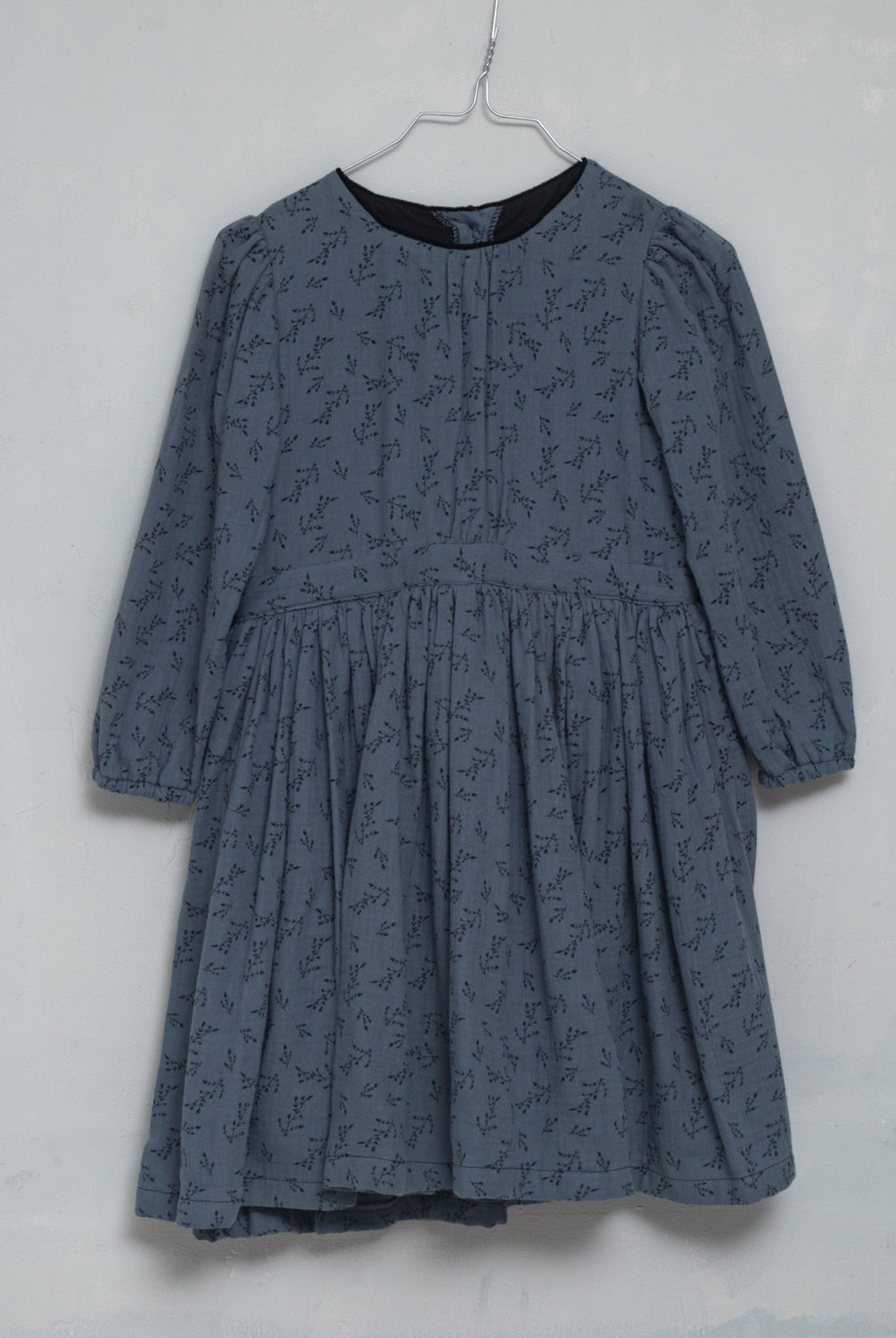 You will love our vintage cut Pandora dress. Contrasting detail on the neck in black. Made in a beautiful double cotton gauze fabric, the print is of small flowers in black on a dark blue background.