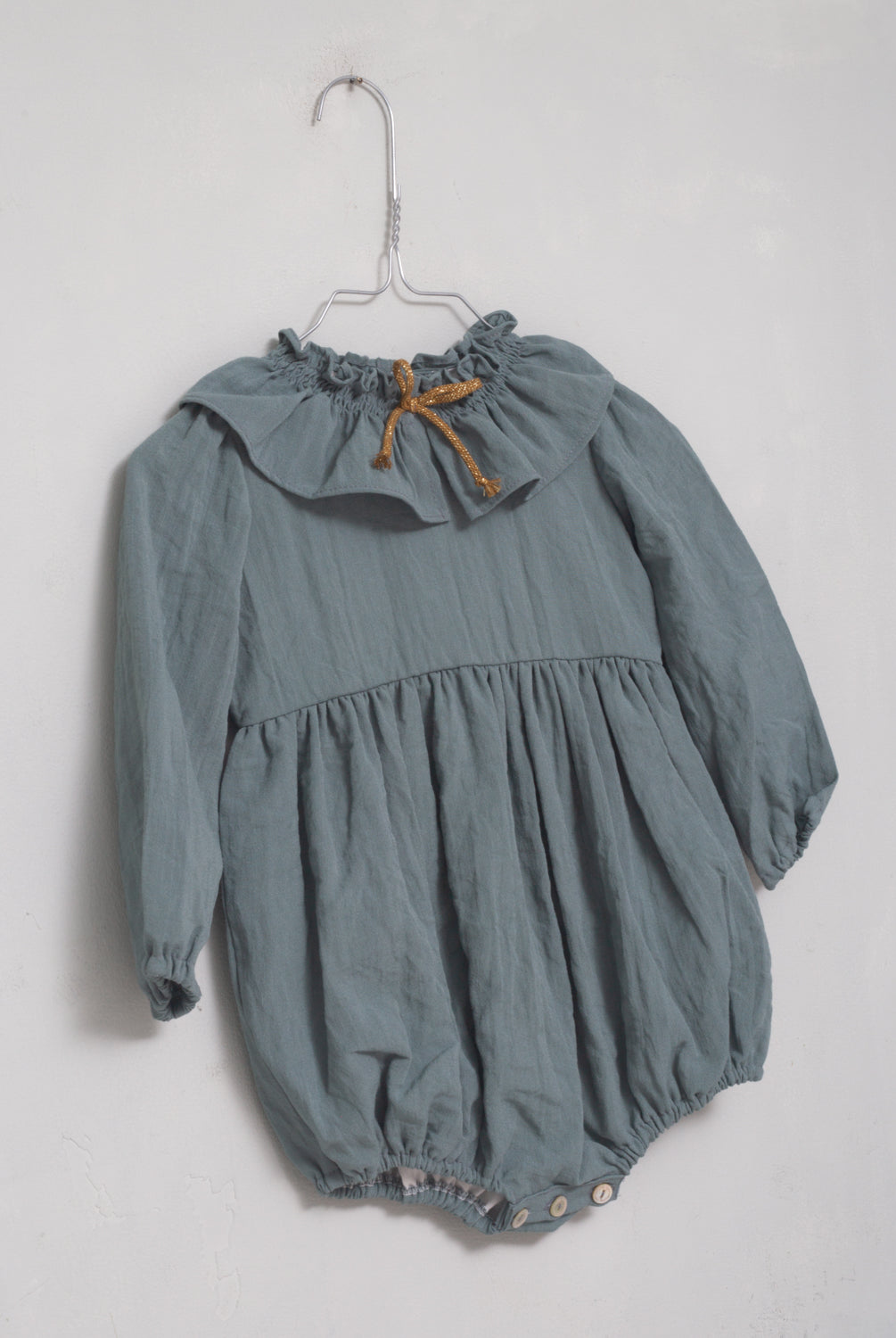 Ranita azul con cuello de volante y lazada en oro para bebe.