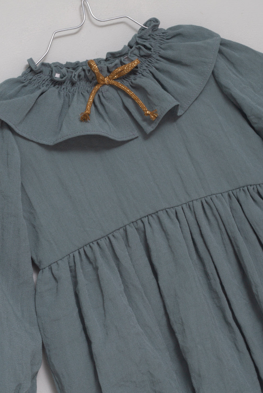 Ranita azul con cuello de volante y lazada en oro para bebe.