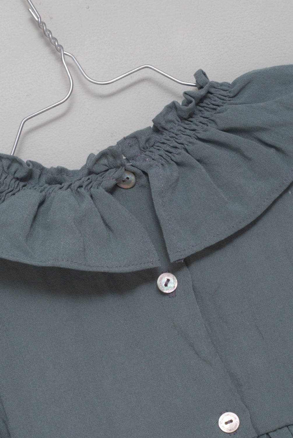 Ranita azul con cuello de volante y lazada en oro para bebe.