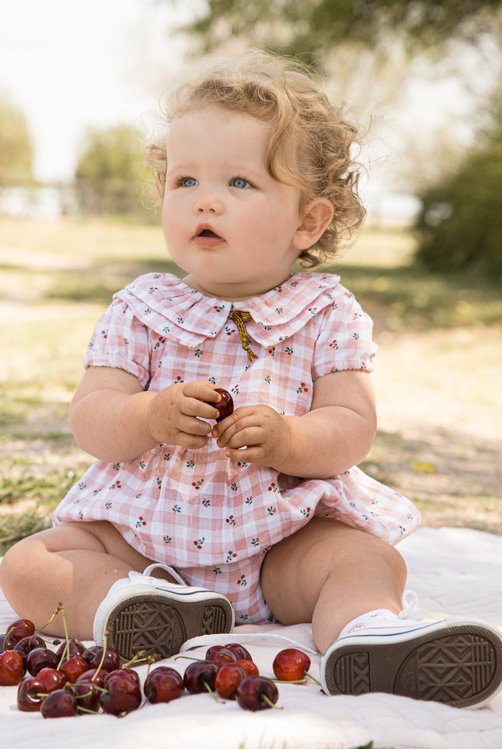 Romper for baby dress in gingham print with flowers. Ruffle neck and gold bow detail. Cosmosophie