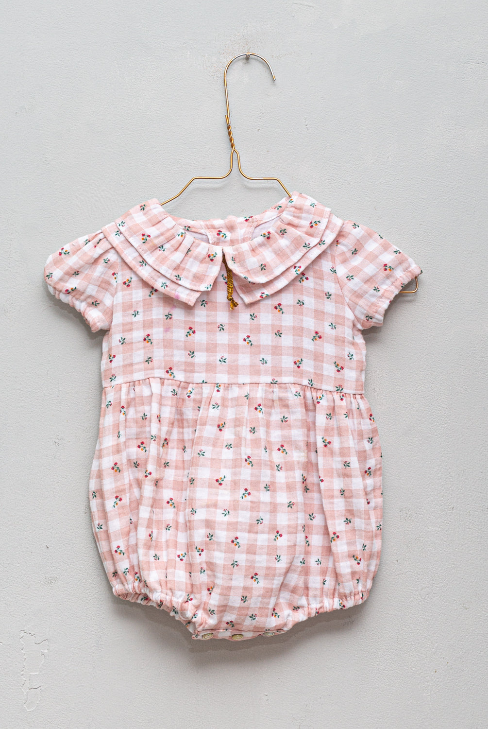 Romper for baby dress in gingham print with flowers. Ruffle neck and gold bow detail. Cosmosophie