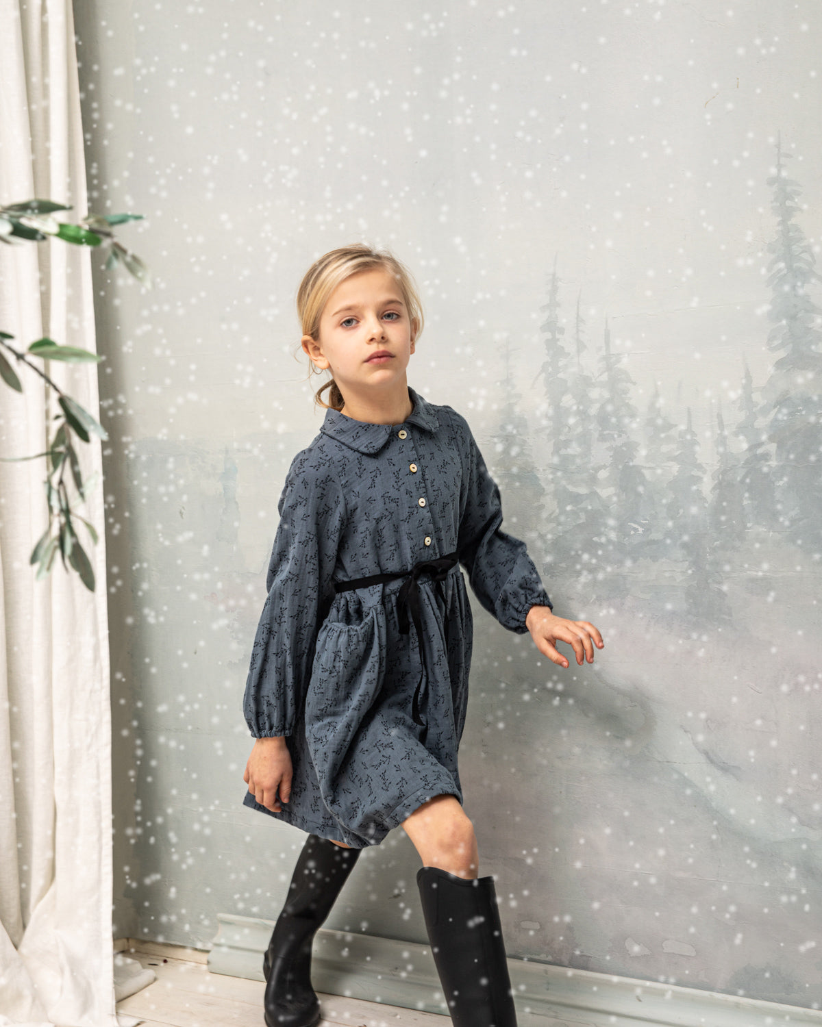 Vestido abierto por delante con botones y cuello bebe. Te encantrá su tejido de doble gasa de color azul con estampado de pequeñas florecitas en negro. Como detalles, lleva una cinta en negro que se anuda en la cintura.