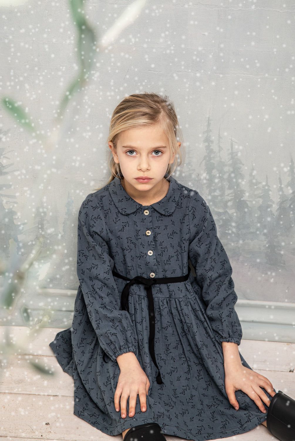 Vestido abierto por delante con botones y cuello bebe. Te encantrá su tejido de doble gasa de color azul con estampado de pequeñas florecitas en negro. Como detalles, lleva una cinta en negro que se anuda en la cintura.