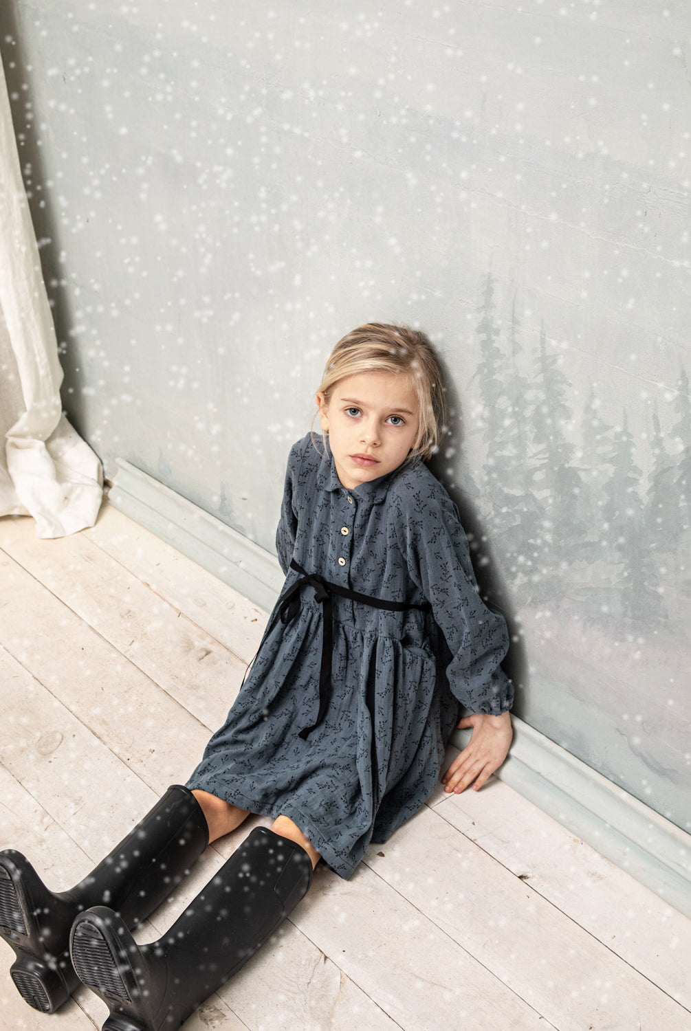 Vestido abierto por delante con botones y cuello bebe. Te encantrá su tejido de doble gasa de color azul con estampado de pequeñas florecitas en negro. Como detalles, lleva una cinta en negro que se anuda en la cintura.