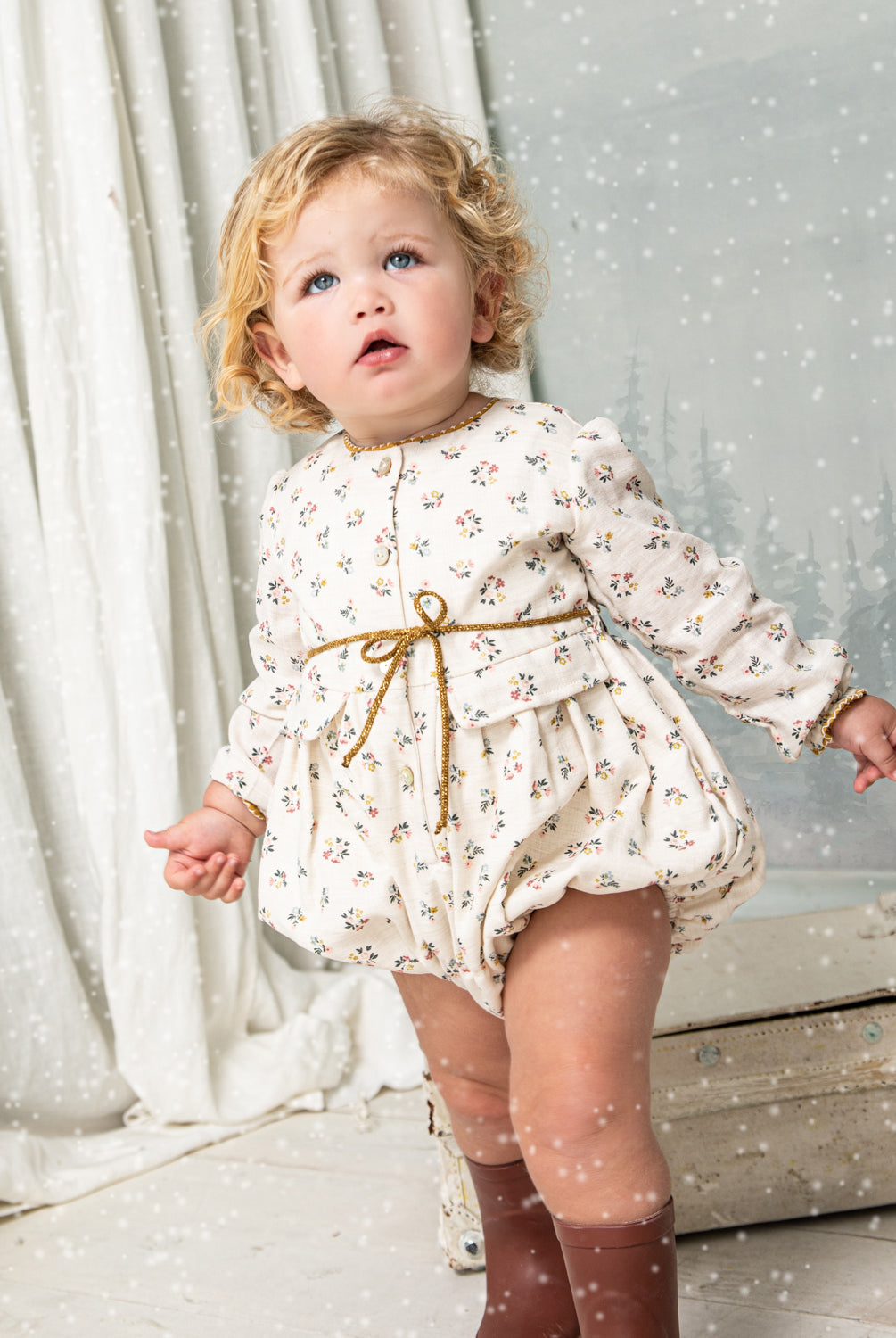Your baby will look beautiful in this floral print romper in blue, pink and mustard on an ecru background. You'll love the contrasting detail on the neck, its decorative pockets and its tie detail at the waist. Front button closure and between legs. Elasticated cuffs for greater comfort.