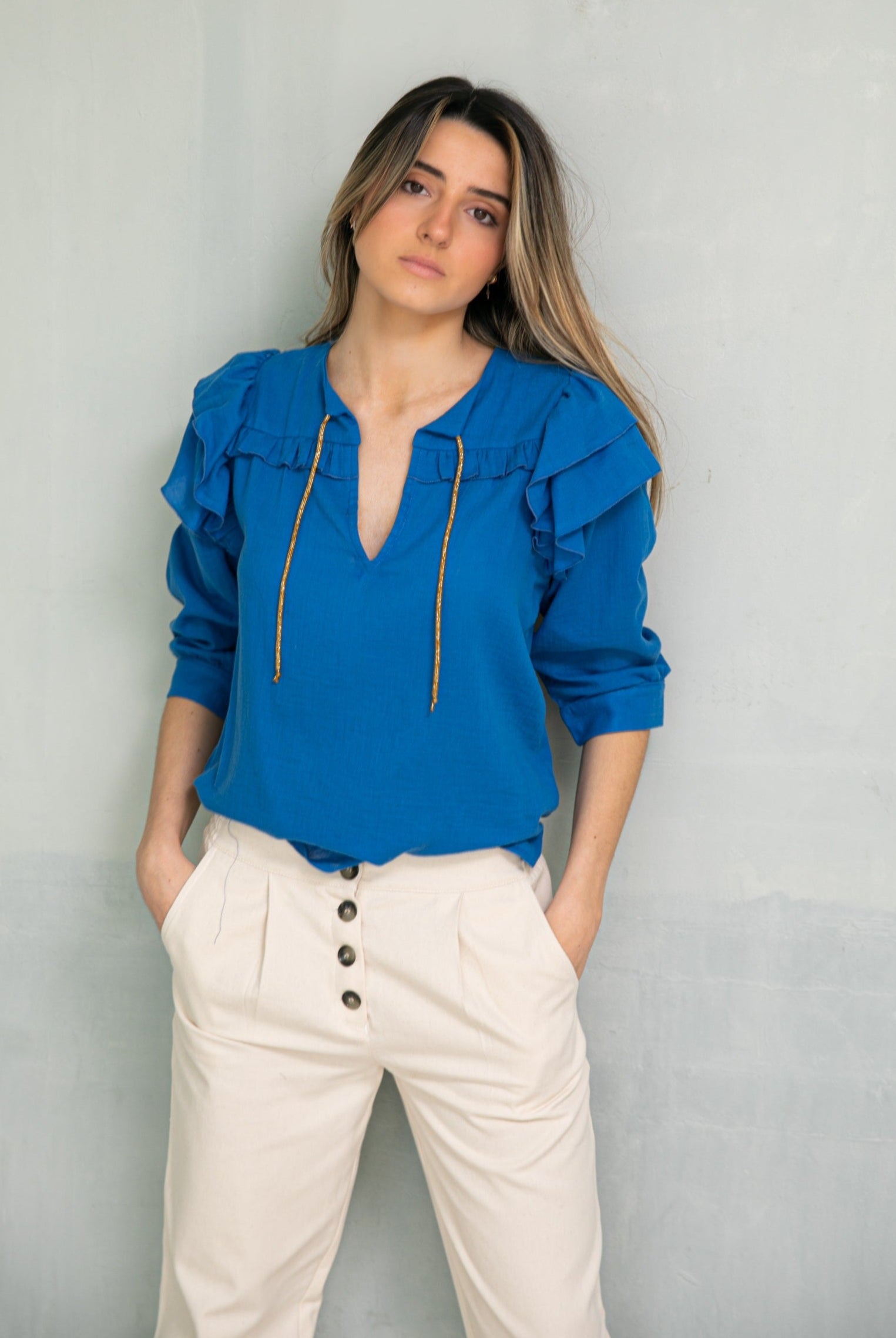 Cyan blue blouse with double ruffle on the sleeve and gold bow on the neck. Three-quarter sleeves and ruffle detail