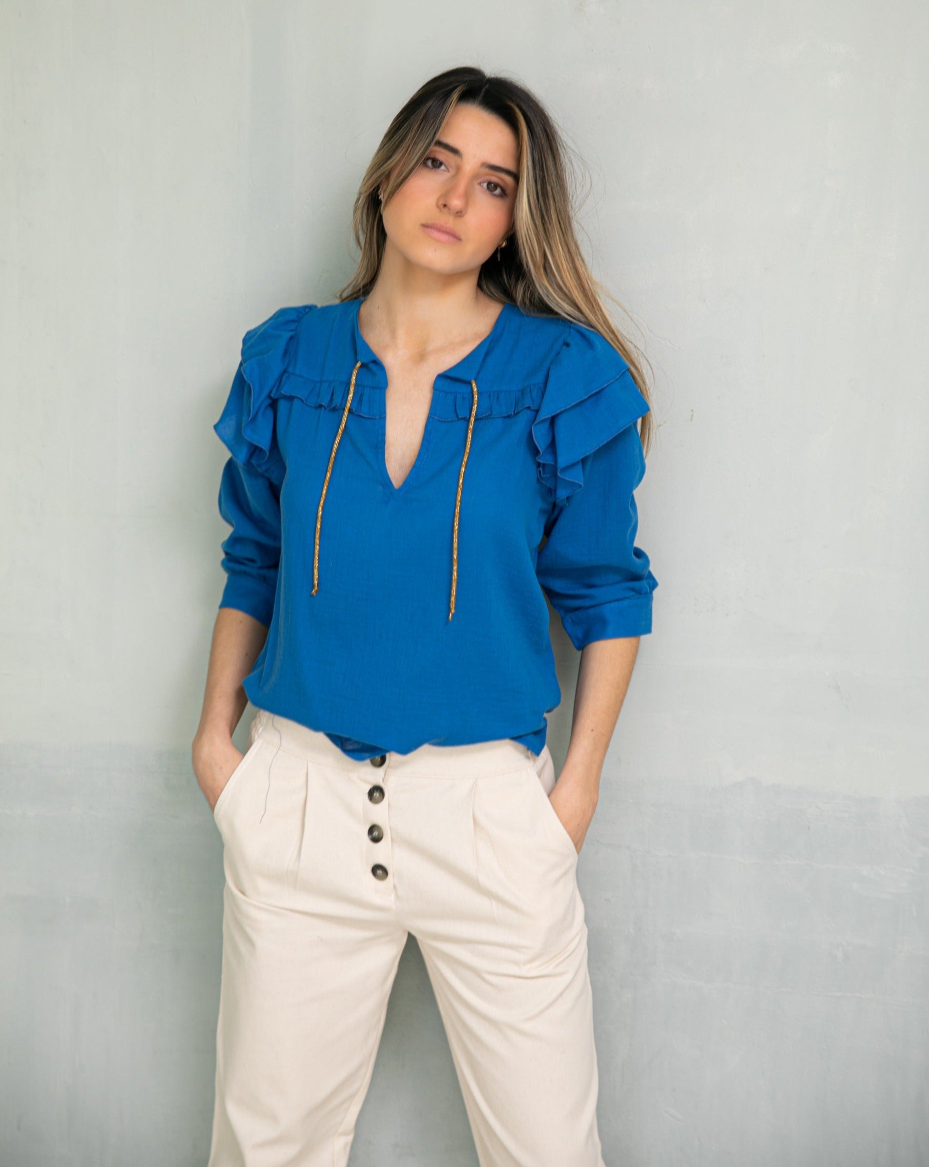 Cyan blue blouse with double ruffle on the sleeve and gold bow on the neck. Three-quarter sleeves and ruffle detail