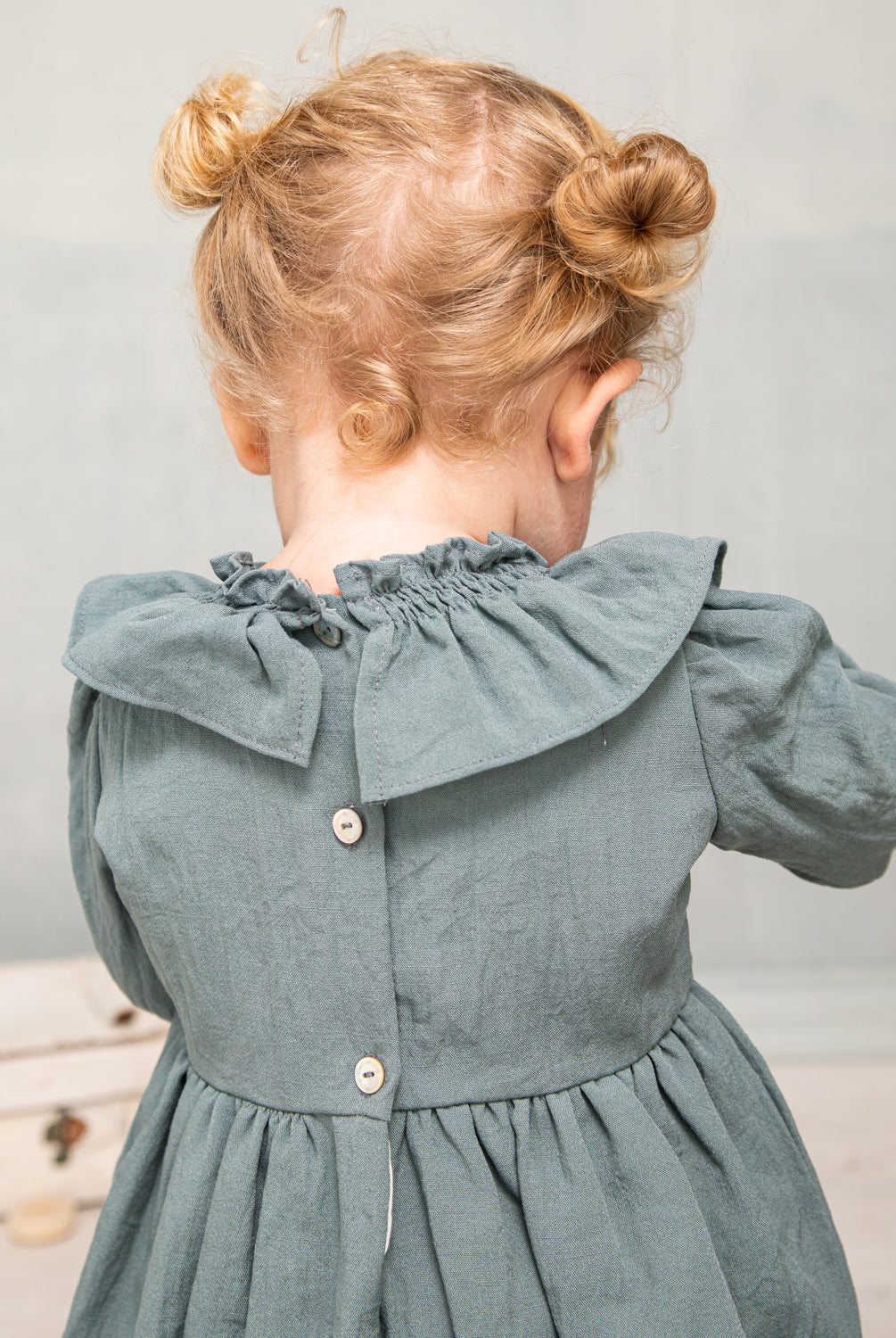 Ranita azul con cuello de volante y lazada en oro para bebe.