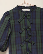 Blusa elegante para niña de cuadros con mangas abullonadas y lazadas delanteras. Diseño atemporal de Cosmosophie para ocasiones especiales.