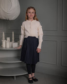 Falda Bert Glow plisada para niña, confeccionada en 100% poliéster con un sutil brillo. Diseño elegante y versátil, confeccionado en España.