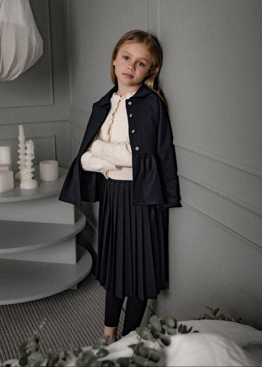 Falda Bert Glow plisada para niña, confeccionada en 100% poliéster con un sutil brillo. Diseño elegante y versátil, confeccionado en España.