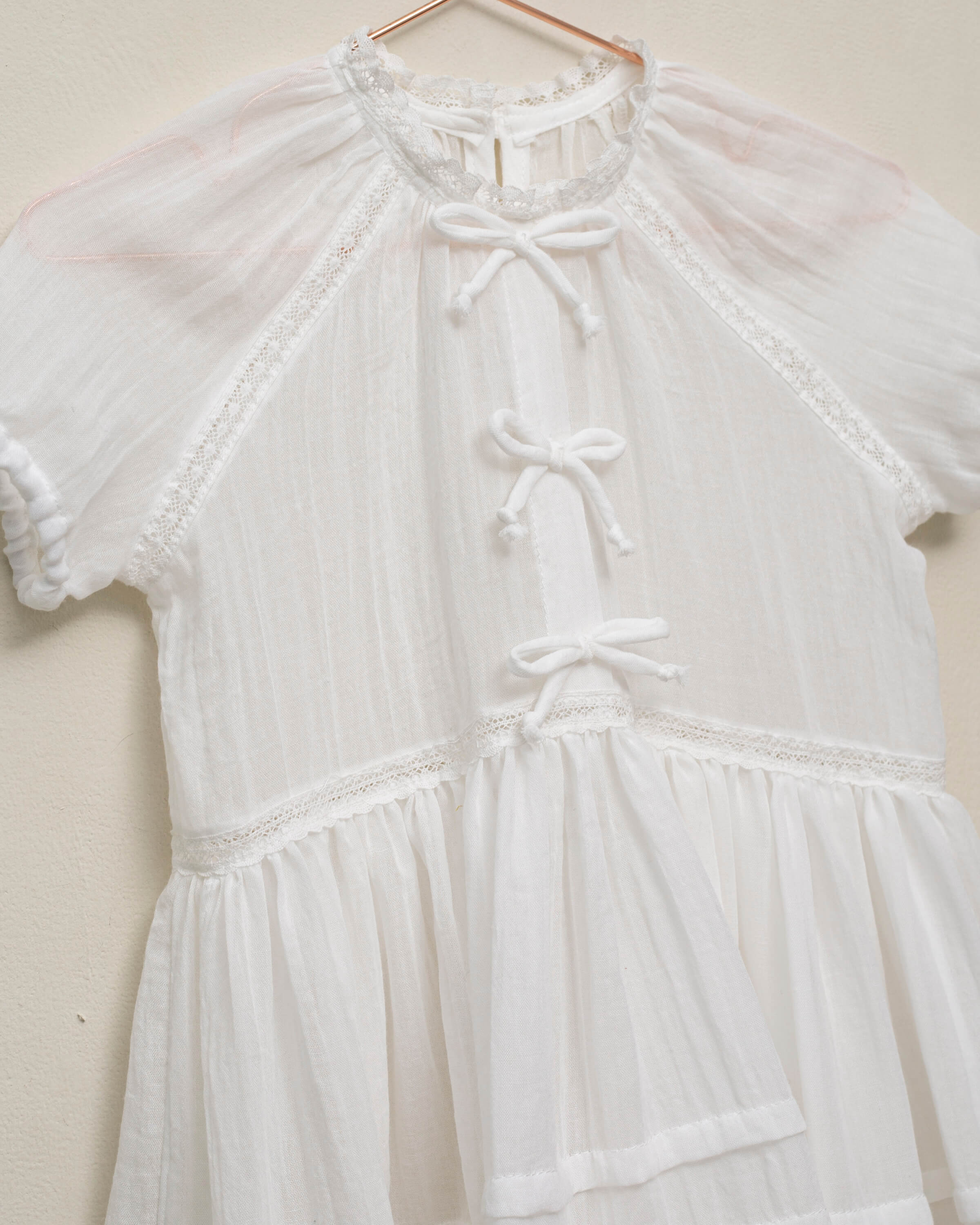 Vestido en blanco roto con lazitos en el pecho y encajes, falda con lorzas y pololos a juego Cosmosophie