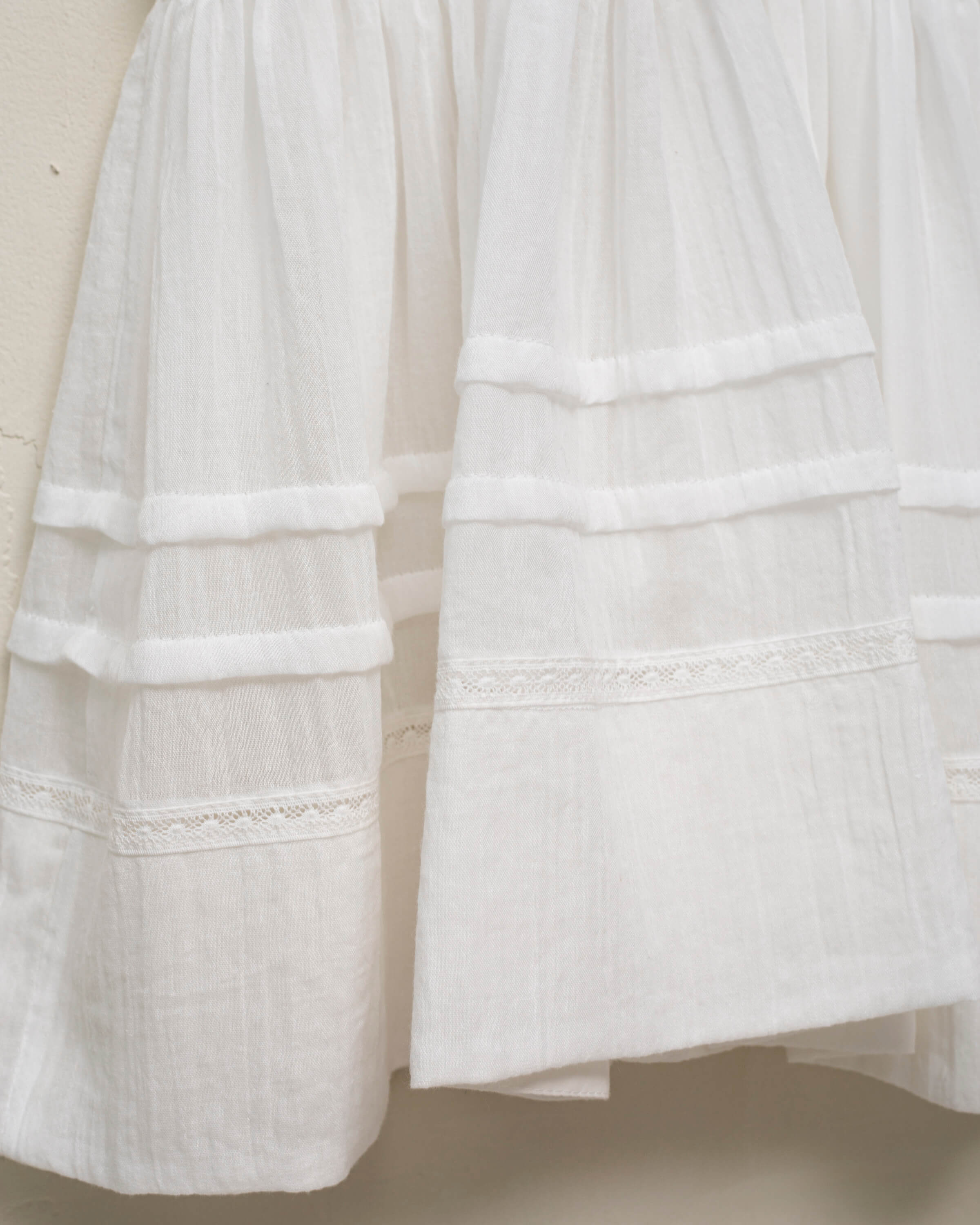 Vestido en blanco roto con lazitos en el pecho y encajes, falda con lorzas y pololos a juego Cosmosophie