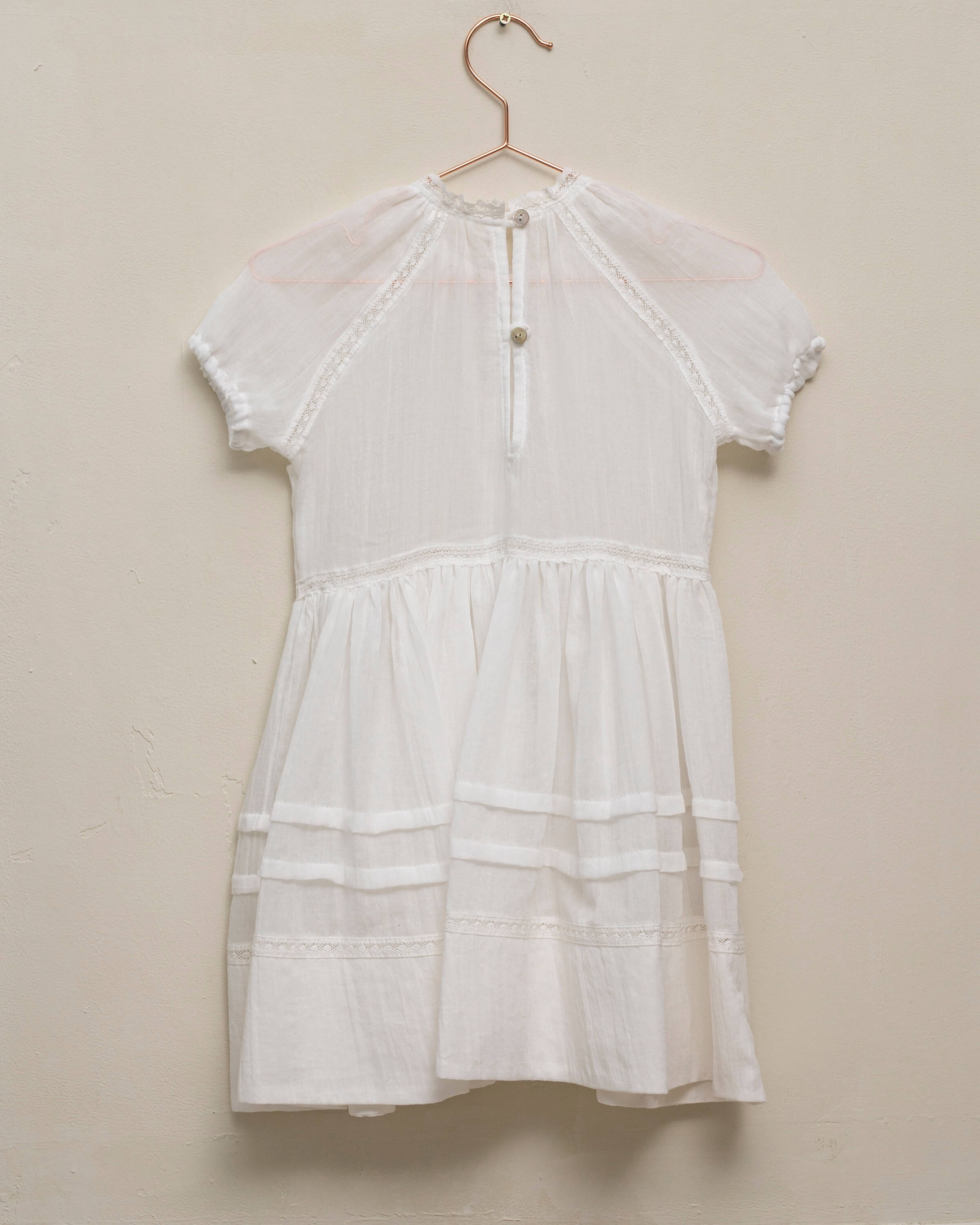 Vestido en blanco roto con lazitos en el pecho y encajes, falda con lorzas y pololos a juego Cosmosophie