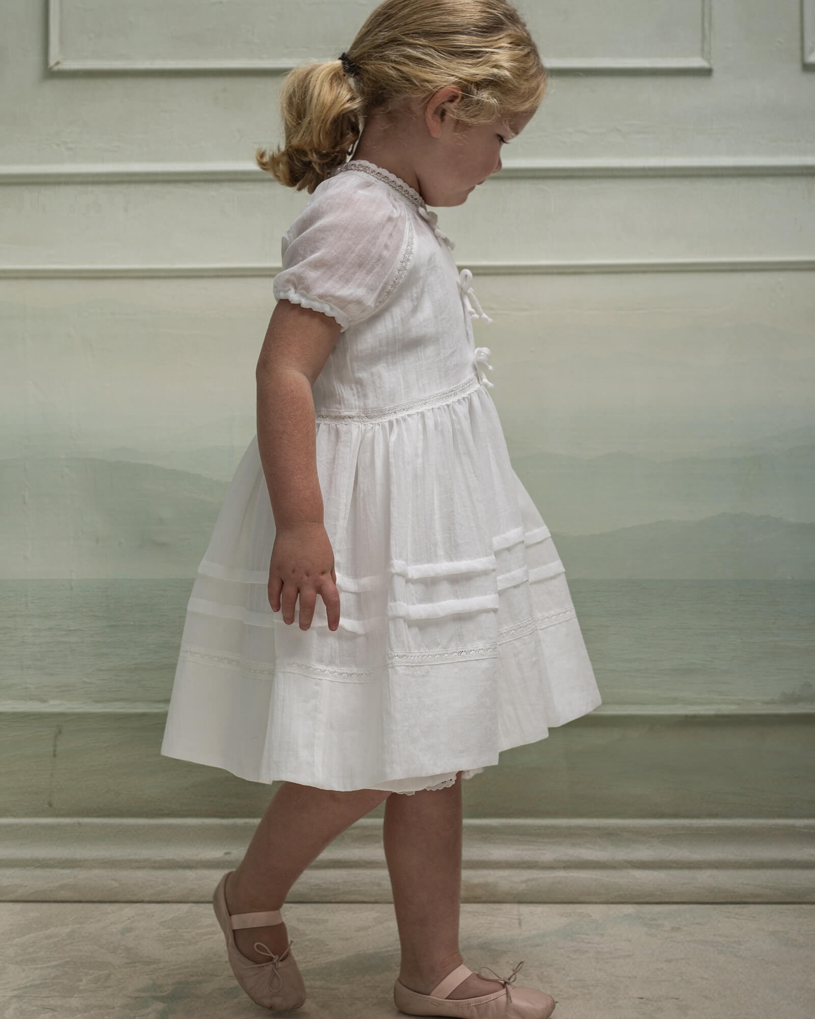 Vestido en blanco roto con lazitos en el pecho y encajes, falda con lorzas y pololos a juego Cosmosophie