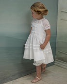 Vestido en blanco roto con lazitos en el pecho y encajes, falda con lorzas y pololos a juego Cosmosophie