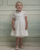 Vestido en blanco roto con lazitos en el pecho y encajes, falda con lorzas y pololos a juego Cosmosophie