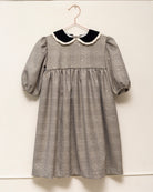 Vestido Tola de niña en cuadro de Gales con lentejuelas, cuello de terciopelo y mangas abullonadas. Diseño romántico y sofisticado.
