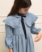 Vestido azul celeste con capita con volantes y lazo negro. cosmosophie