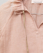 Blusa de mujer rosa con efecto jacquard, cuello de volantes deshilachados y cordones dorados. Diseño femenino y especial.