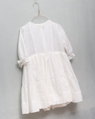 Detail of white dress for girl with ruffled skirt and short summer sleeves. Luxury dress for a wedding or first communion.