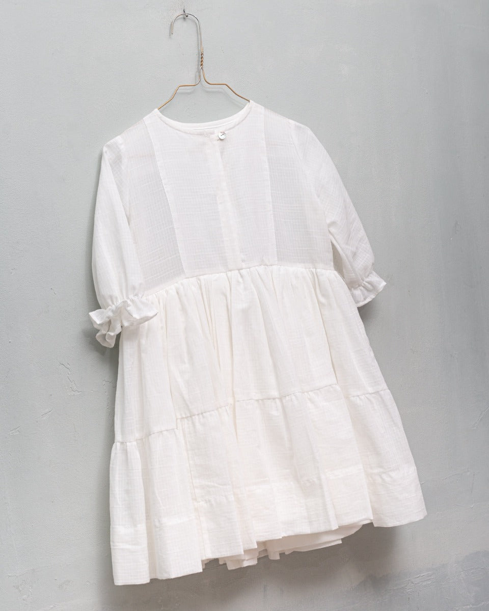 Detail of white dress for girl with ruffled skirt and short summer sleeves. Luxury dress for a wedding or first communion.