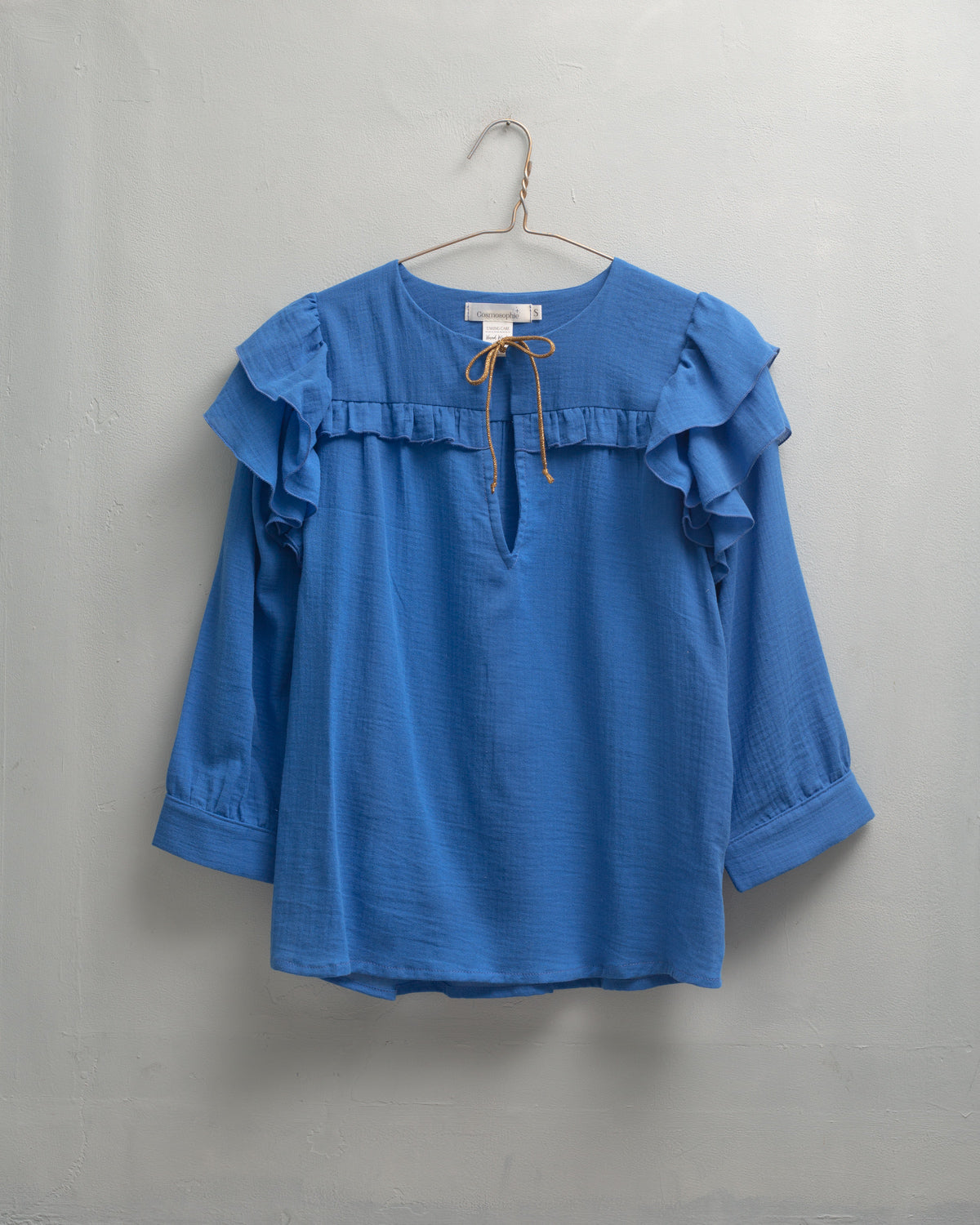 Blusa en algodon vaporoso azul cian con doble volante en el hombro y lazada en oro