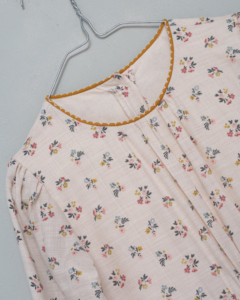 You will love our vintage cut Pandora dress. Contrasting neck detail in mustard color. Made in a beautiful cotton fabric, the print is of little flowers in shades of blue, pink and mustard on an ecru background.