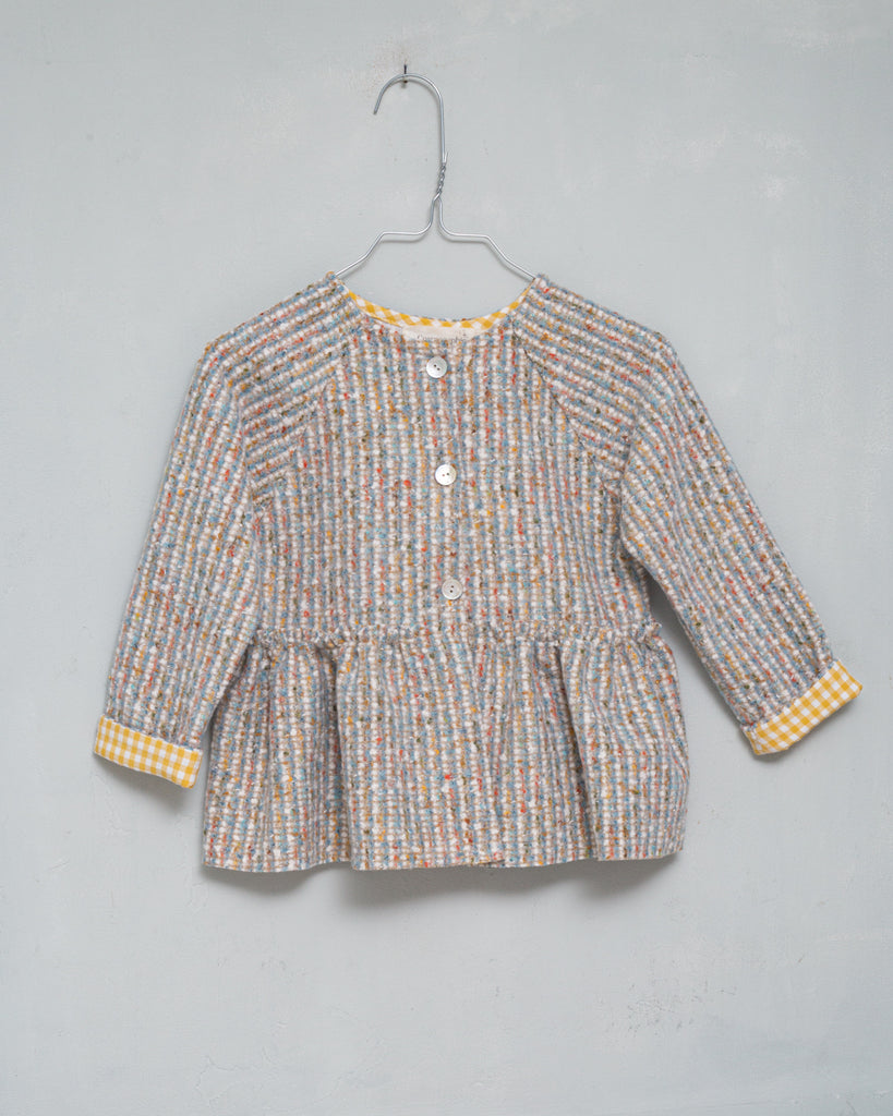 Preciosa chaqueta realizada en tweed en tonos crudos, azules y rosa con un toque de dorado. Te encantará su detalle en el interior y en la manga de vichy amarillo. Perfecto para combinar con nuestro pichi Homa.
