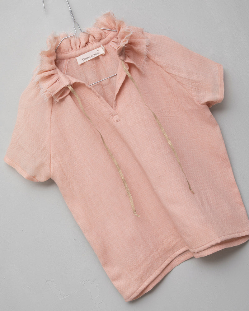 Blusa de mujer rosa con efecto jacquard, cuello de volantes deshilachados y cordones dorados. Diseño femenino y especial.