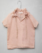 Blusa de mujer rosa con efecto jacquard, cuello de volantes deshilachados y cordones dorados. Diseño femenino y especial.