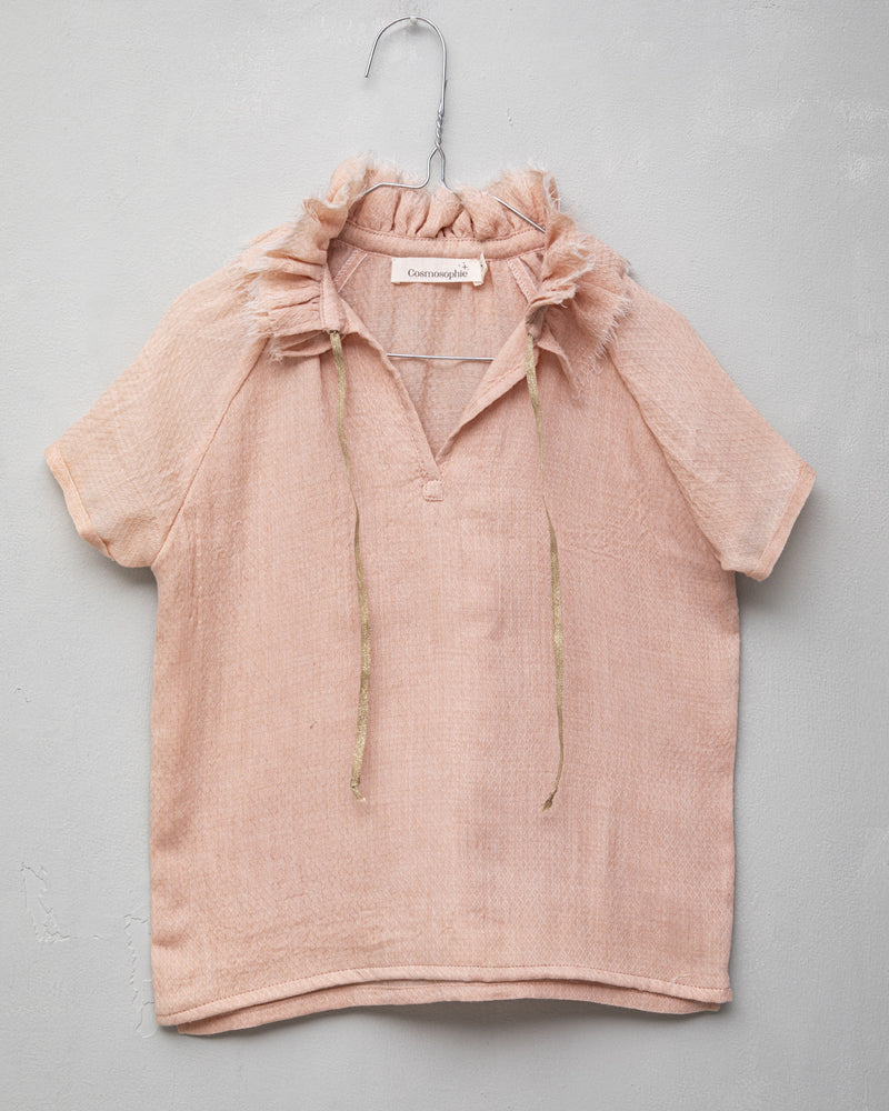 Blusa de mujer rosa con efecto jacquard, cuello de volantes deshilachados y cordones dorados. Diseño femenino y especial.