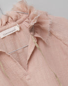 Blusa de mujer rosa con efecto jacquard, cuello de volantes deshilachados y cordones dorados. Diseño femenino y especial.